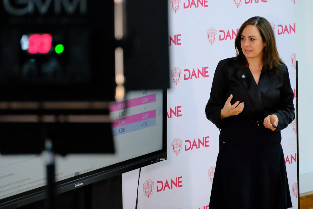 Piedad Urdinola, Directora del Departamento Administrativo Nacional de Estadística (DANE) en un evento televisado, con el logo del DANE de fondo